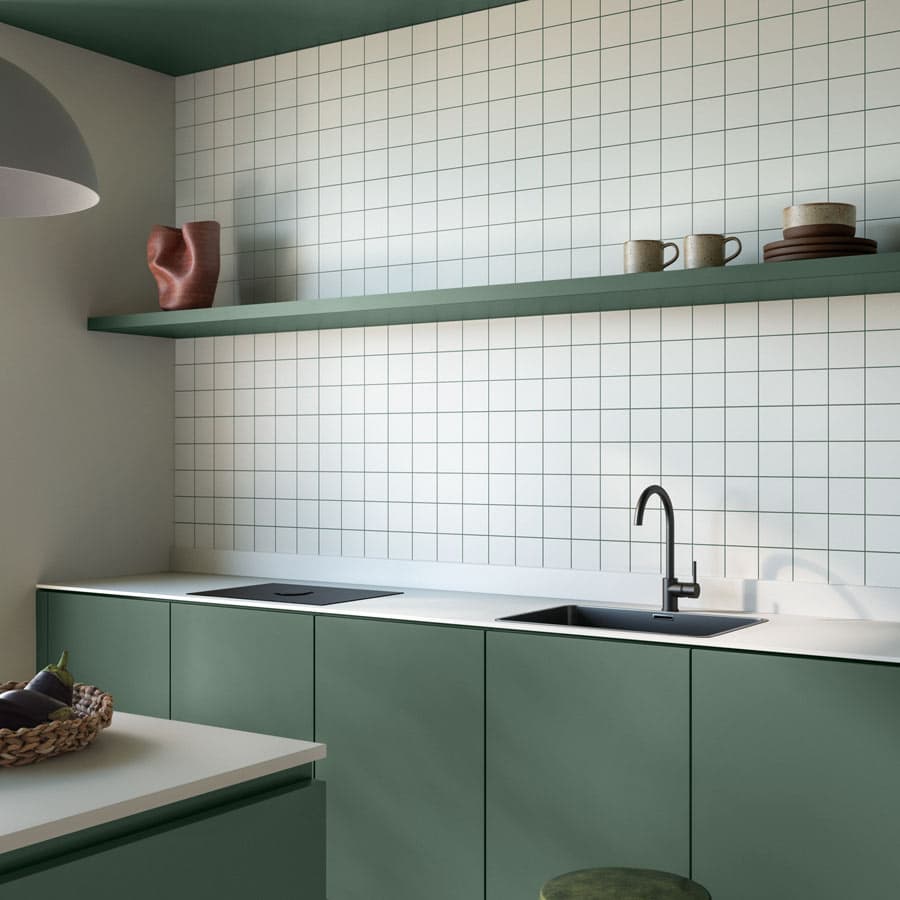 Minimalist kitchen with green cabinets, white tiled backsplash, black faucet, and open shelf holding pottery and cups. Basket on counter.
