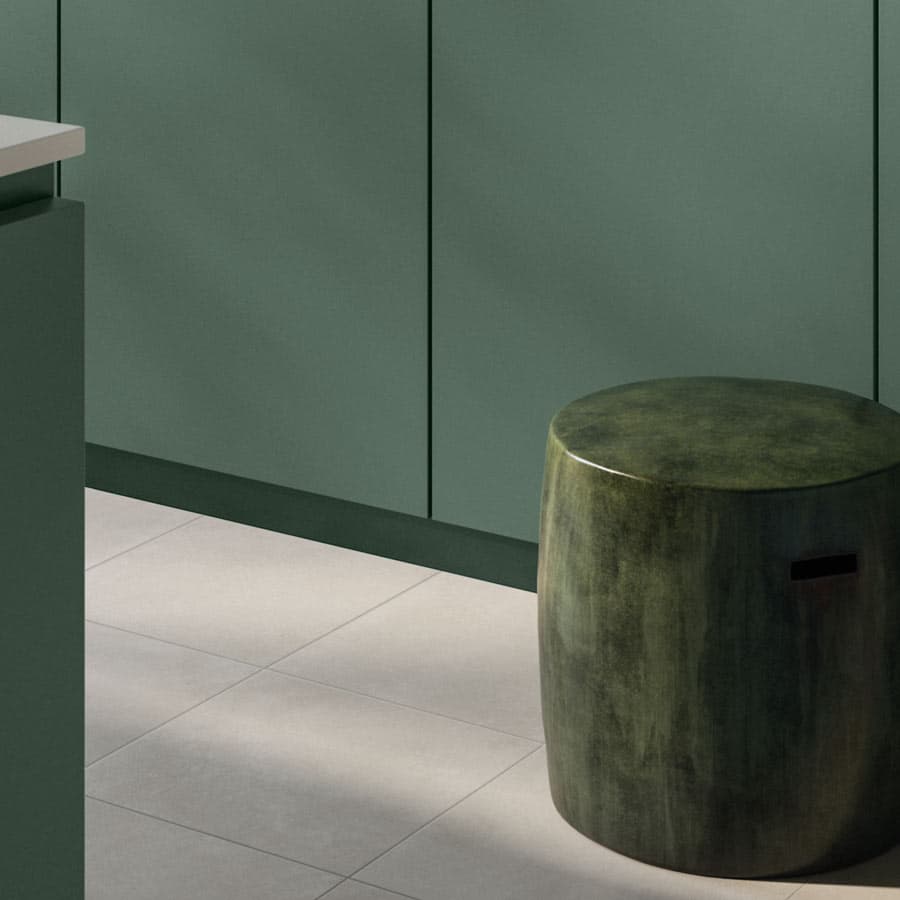 Modern kitchen with green cabinets, a glossy green cylindrical stool, and light gray tiled flooring. Minimalist and elegant design.